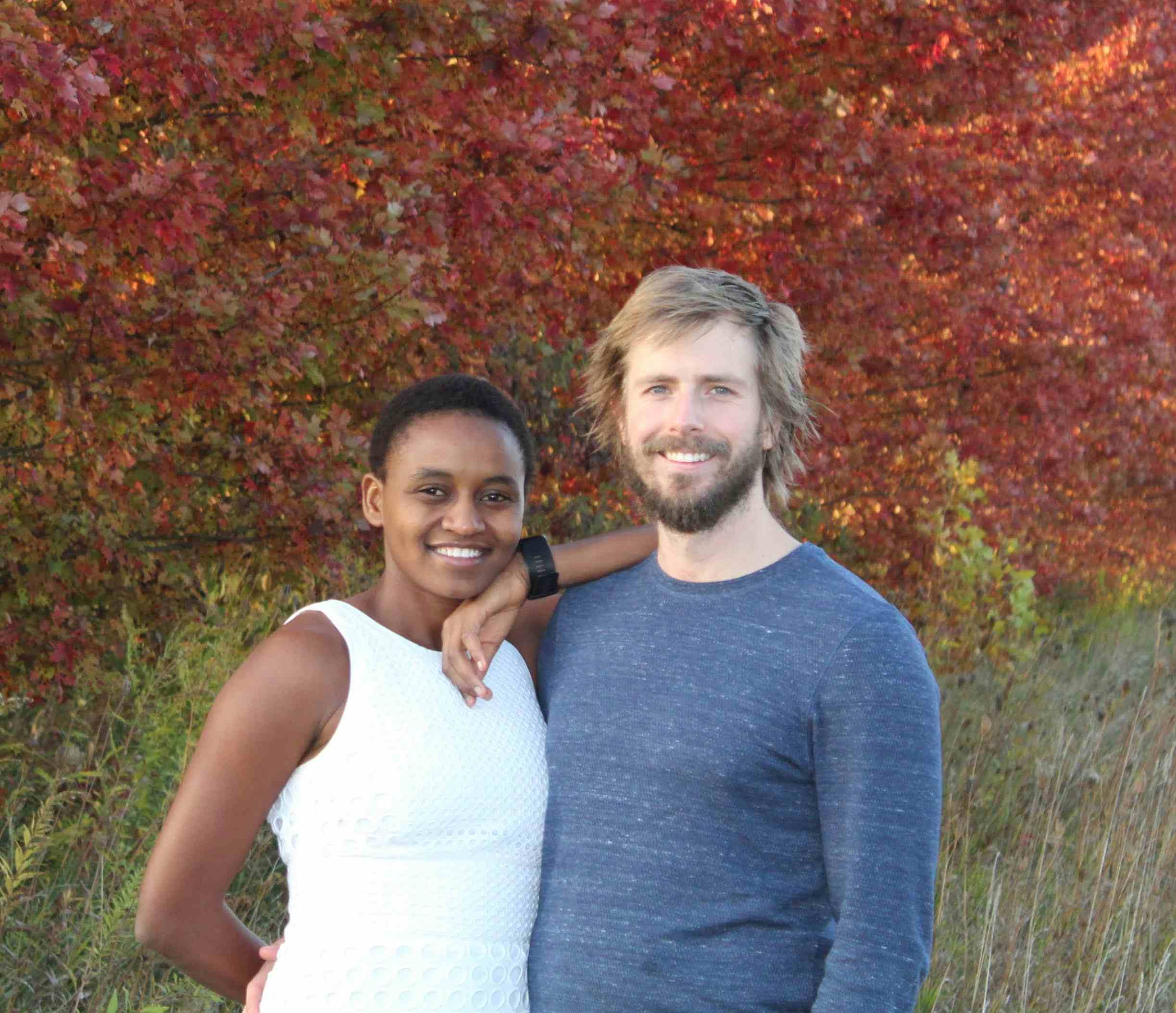 Nelly Cheboi and Tyler Cinnamon standing in front of colorful fall pictures